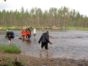 Nuoria ylittämässä jokea kahlaamalla.