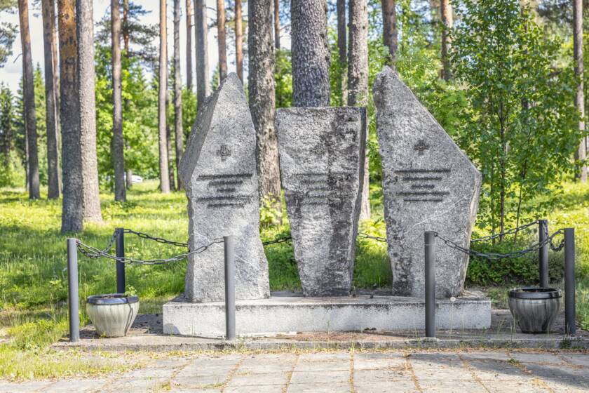 Kolmesta pystyssä seisovaa kivenlohkaretta, joihin on kiinnitetty metallimerkit ja tekstiä metallikirjaimin.