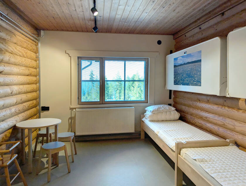 Pienessä makuuhuoneessa on kaksi sänkyä lattialla, ja kaksi sänkyä on seinällä, nostettuna seinää vasten.