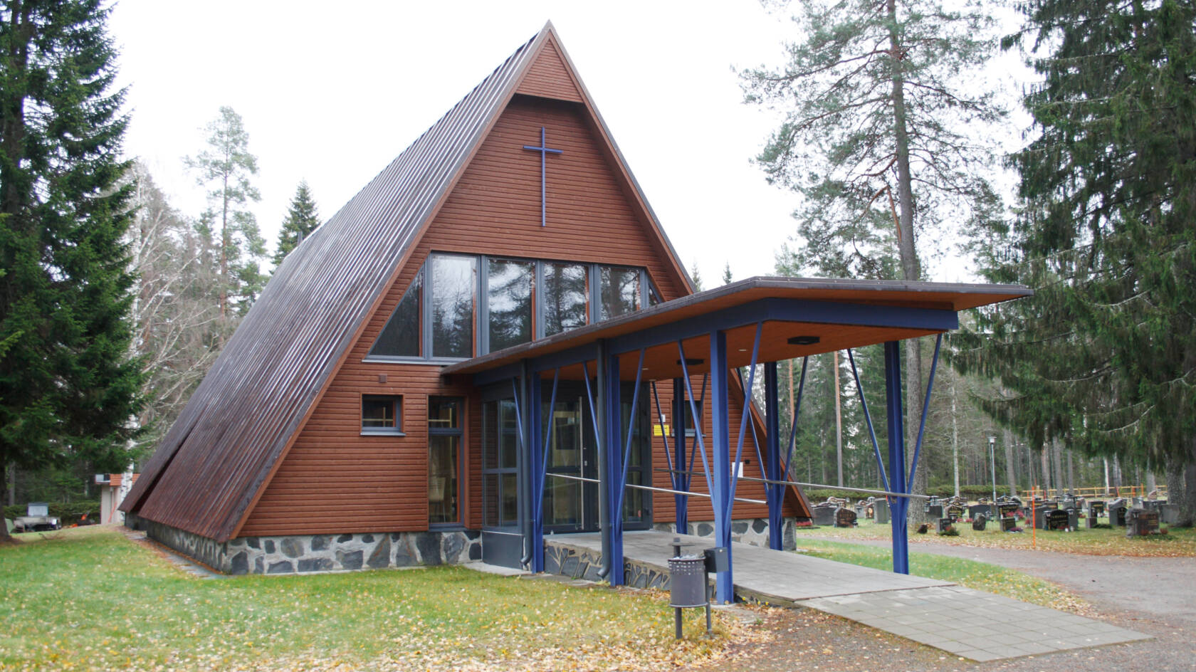 Hautausmaan keskellä sijaitsevan kolmiomuotoisen kappelin etuosassa on pylväiden kannattama katos.